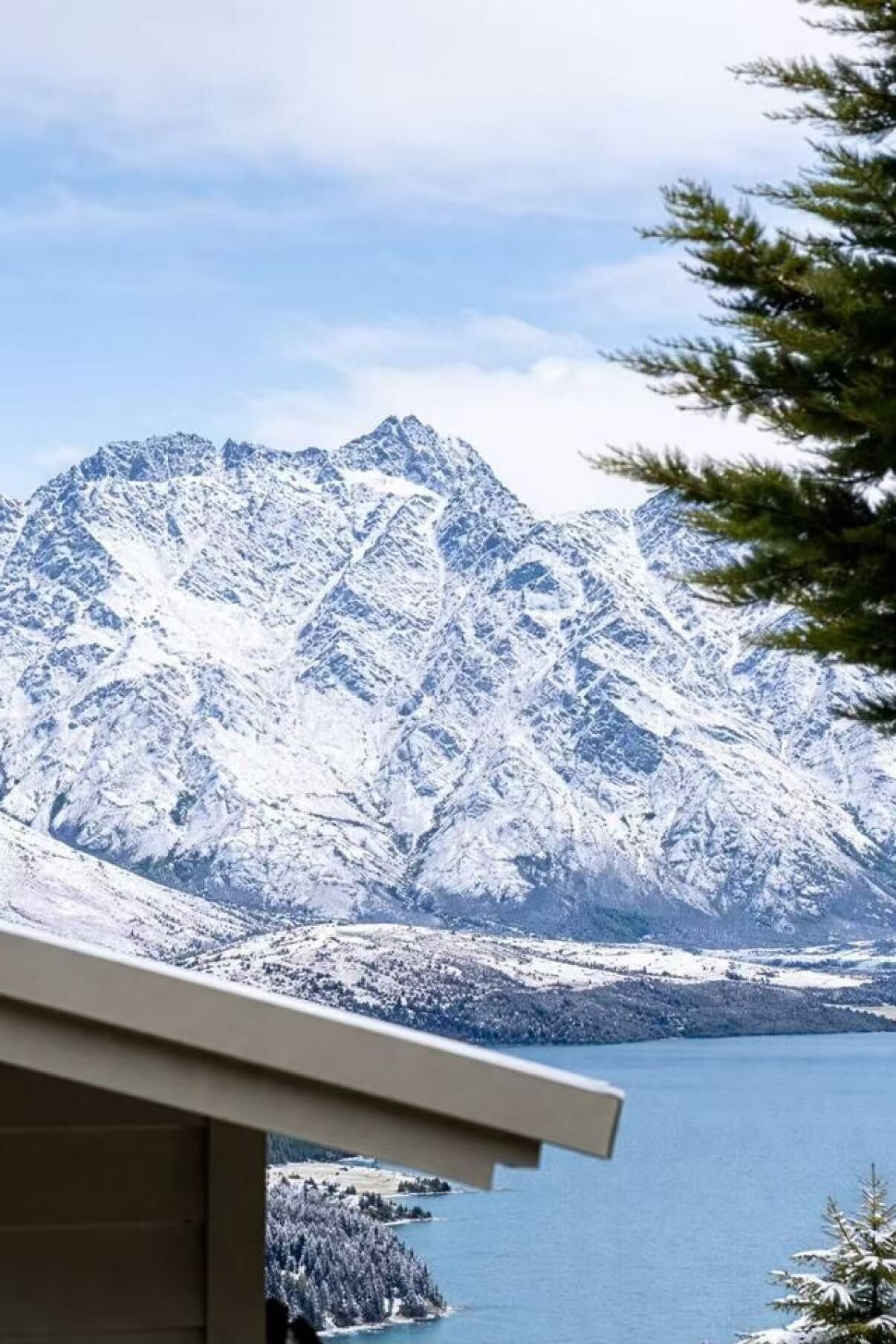 A mountain landscape with snow-covered peaks and a body of water in the foreground.