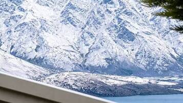A mountain landscape with snow-covered peaks and a body of water in the foreground.