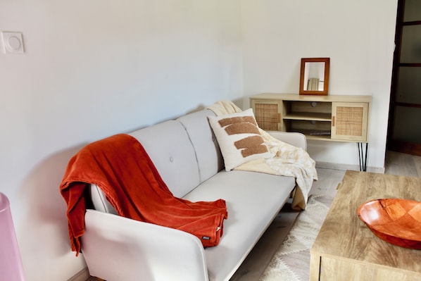 A modern living room with a sofa, a wooden coffee table, and a cabinet with a mirror.