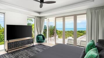 A modern bedroom with a large bed, a TV, and a balcony with a view.