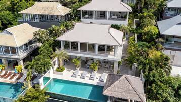 A multi-story resort with a swimming pool, lounge areas, and a thatched-roof structure.