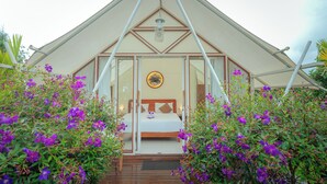 A triangular-roofed structure with a bed and a circular wall decoration. - Svargan Lakeside Glamping & Restaurant (Baturiti)