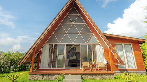 A modern house with a triangular roof, large glass windows, and a wooden deck. - Svargan Lakeside Glamping & Restaurant (Baturiti)