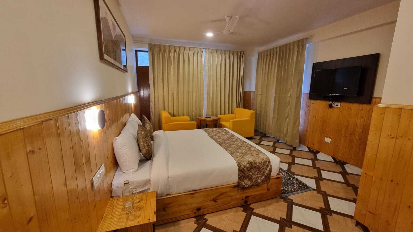 A hotel room with a wooden bed, a TV, a small table, and a chair.