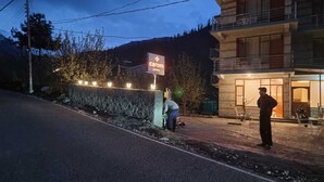 A building with a sign reading 'Carom Inn' and a person standing on the sidewalk. - Carom Inn (Manali)