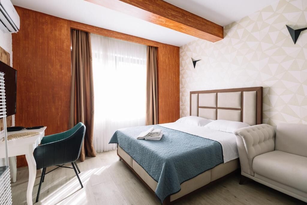 A hotel room with a bed, a desk, a chair, and a TV.