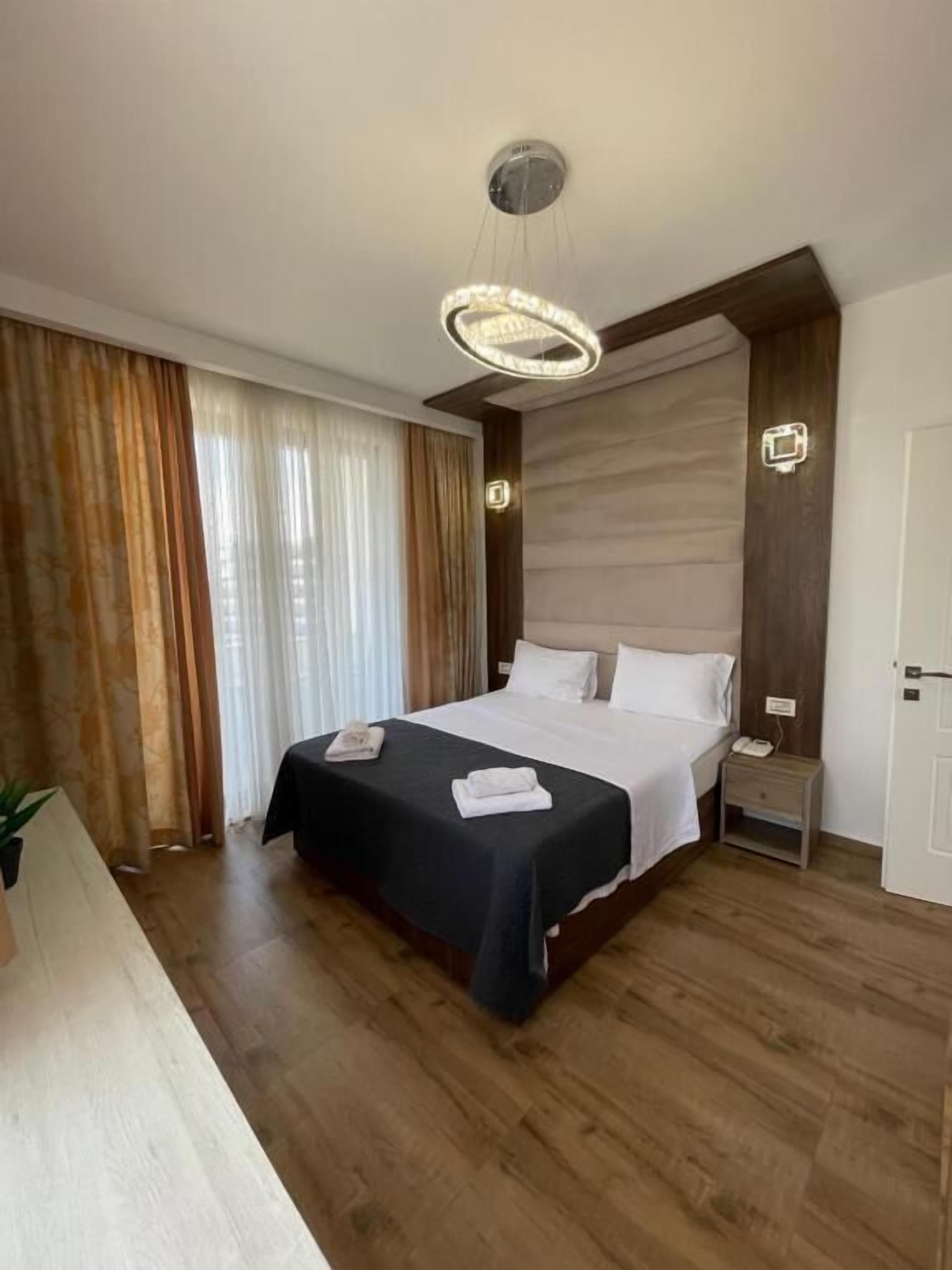 Een hotelkamer met een groot bed, nachtkastjes, een bureau en een kroonluchter.