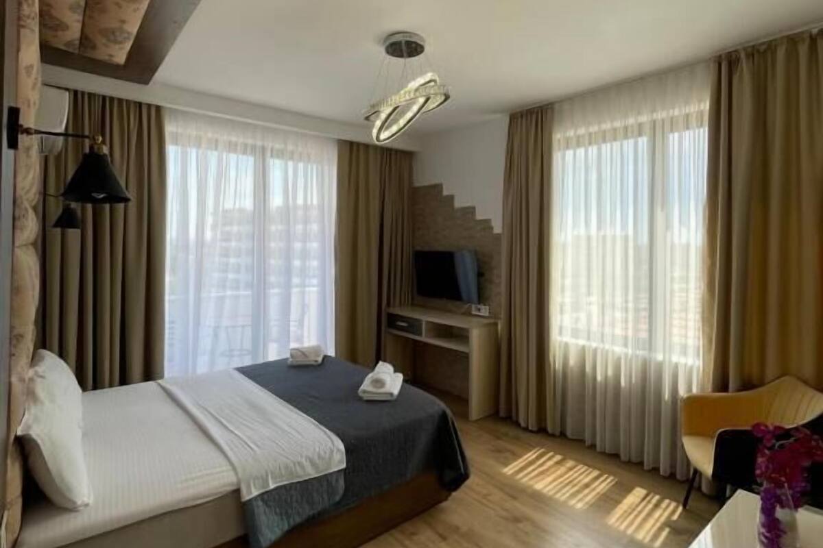 A hotel room with a bed, a desk, a TV, and a staircase.