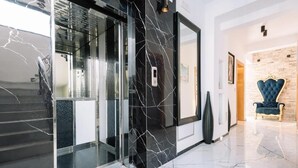 A modern lobby with a glass door, a marble floor, and a blue upholstered chair.
