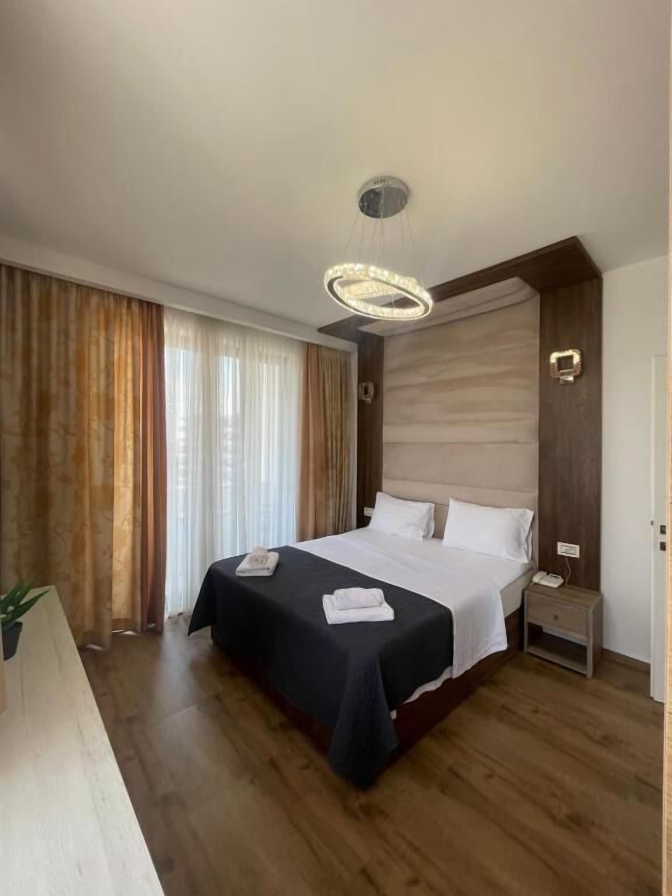 Habitación de hotel con una cama grande, una mesita de noche, lámparas y cortinas.