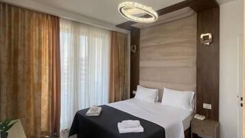Habitación de hotel con una cama grande, una mesita de noche, lámparas y cortinas.