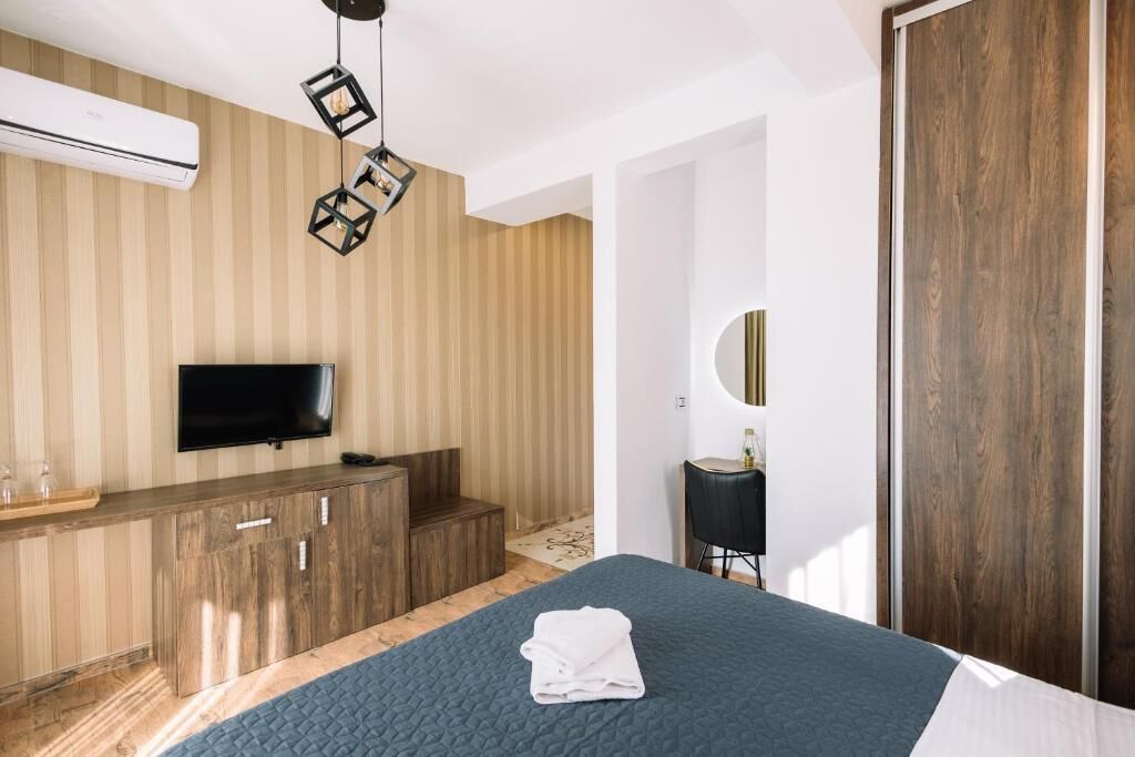 Ein Schlafzimmer mit Bett, Fernseher, Holzschrank und Spiegel.