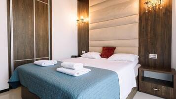 Una habitación de hotel con una cama grande, dos mesitas de noche y una lámpara fijada en la pared.