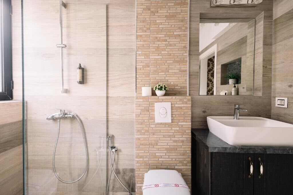 A modern bathroom with a glass shower enclosure, a white sink, and a dark cabinet.