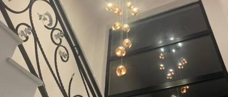 A staircase with a decorative railing and a hanging light fixture.
