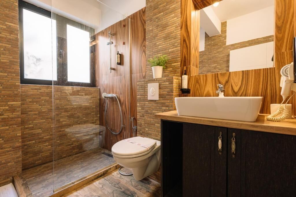 A modern bathroom with a large mirror, a white sink, and a toilet.