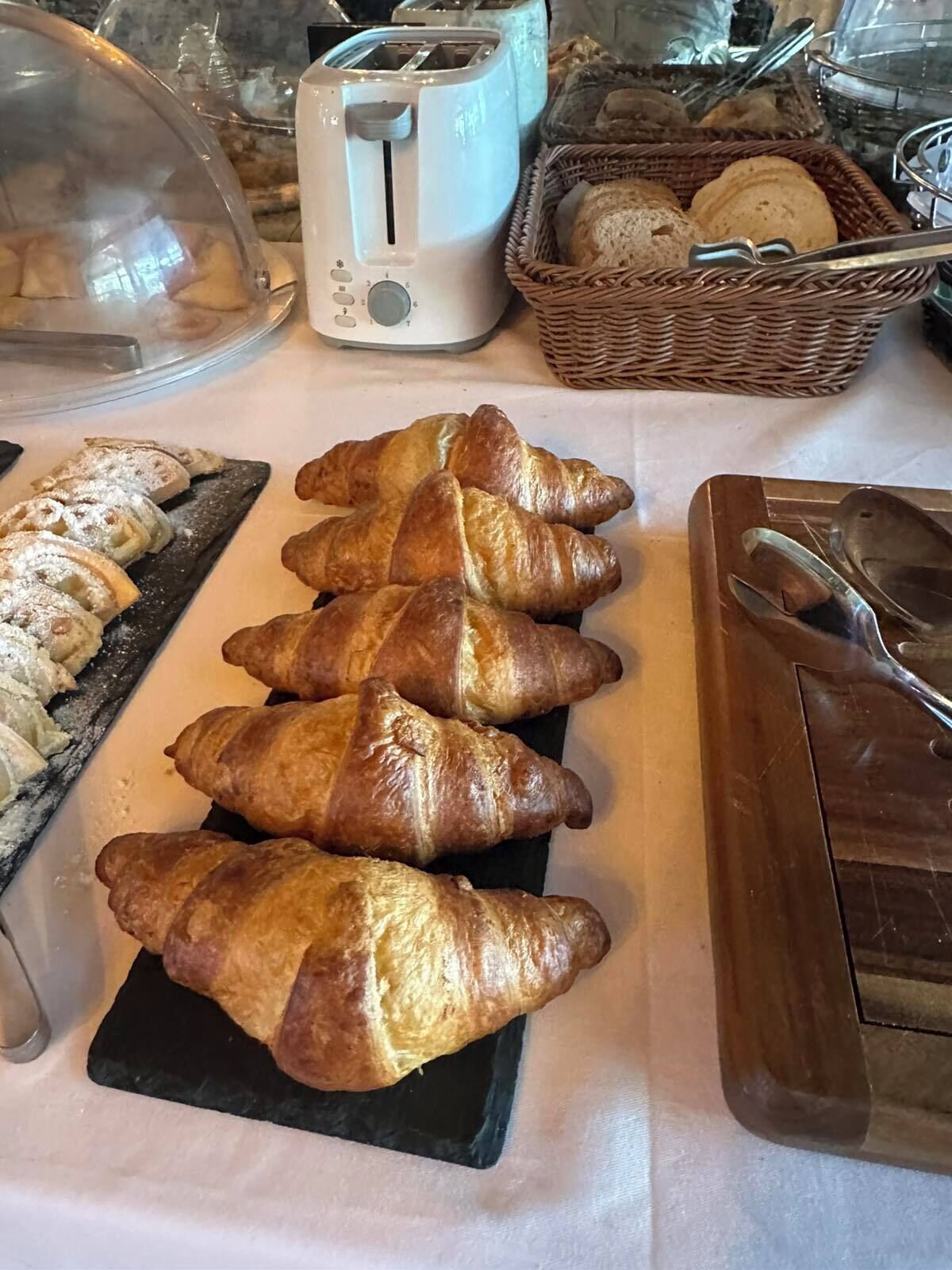 Un buffet de petit-déjeuner avec des croissants, du pain et un grille-pain.
