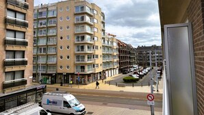 A multi-story residential building with balconies, a van parked on the street, and a pedestrian crossing. - Modern Stay With Balcony & Seaview (Middelkerke)