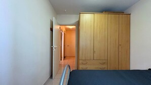 A bedroom with a bed, wooden wardrobe, and a door leading to another room. - Modern Stay With Balcony & Seaview (Middelkerke)