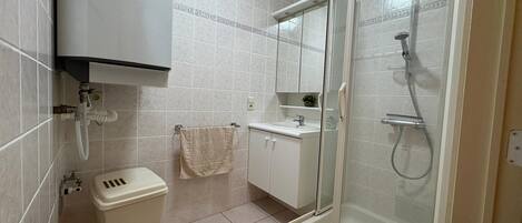 Une salle de bain équipée d’une douche, de toilettes, d’un lavabo et d’un meuble de rangement.