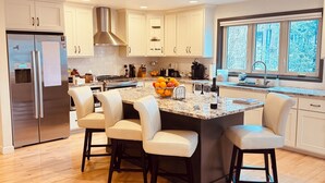 Una cocina moderna con una isla central, muebles blancos y un ventanal grande.