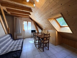 Ein gemütliches Schlafzimmer im Dachgeschoss mit schrägen Wänden, einem Bett, einem Schreibtisch und einem Fenster.