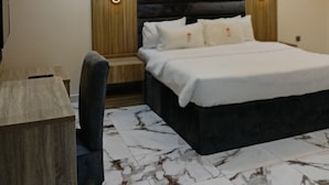 A modern bedroom with a large bed, wooden headboard, and a desk.