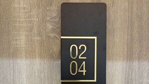 A black square with the numbers '02 04' in gold on a wooden surface.