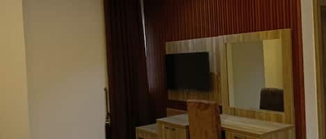 Un dormitorio moderno con una cama, un escritorio de madera, un televisor y un espejo.