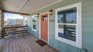 A wooden deck with two chairs and a table, a door with the number 109, and a window with blinds. - 3 BD Family Home | Extd Stays | Pets Ok (Aransas Pass)