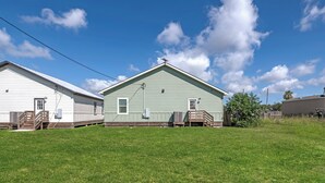 Two single-story houses with front porches, a grassy yard, and a clear blue sky. - 3 BD Family Home | Extd Stays | Pets Ok (Aransas Pass)