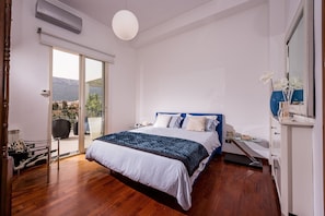 Ein Schlafzimmer mit einem Bett, einem Nachttisch, einer Kommode und einer Schiebetür, die auf einen Balkon führt.
