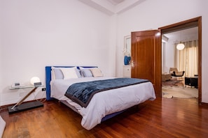 Ein Schlafzimmer mit Bett, Nachttisch, Lampe und Spiegel.