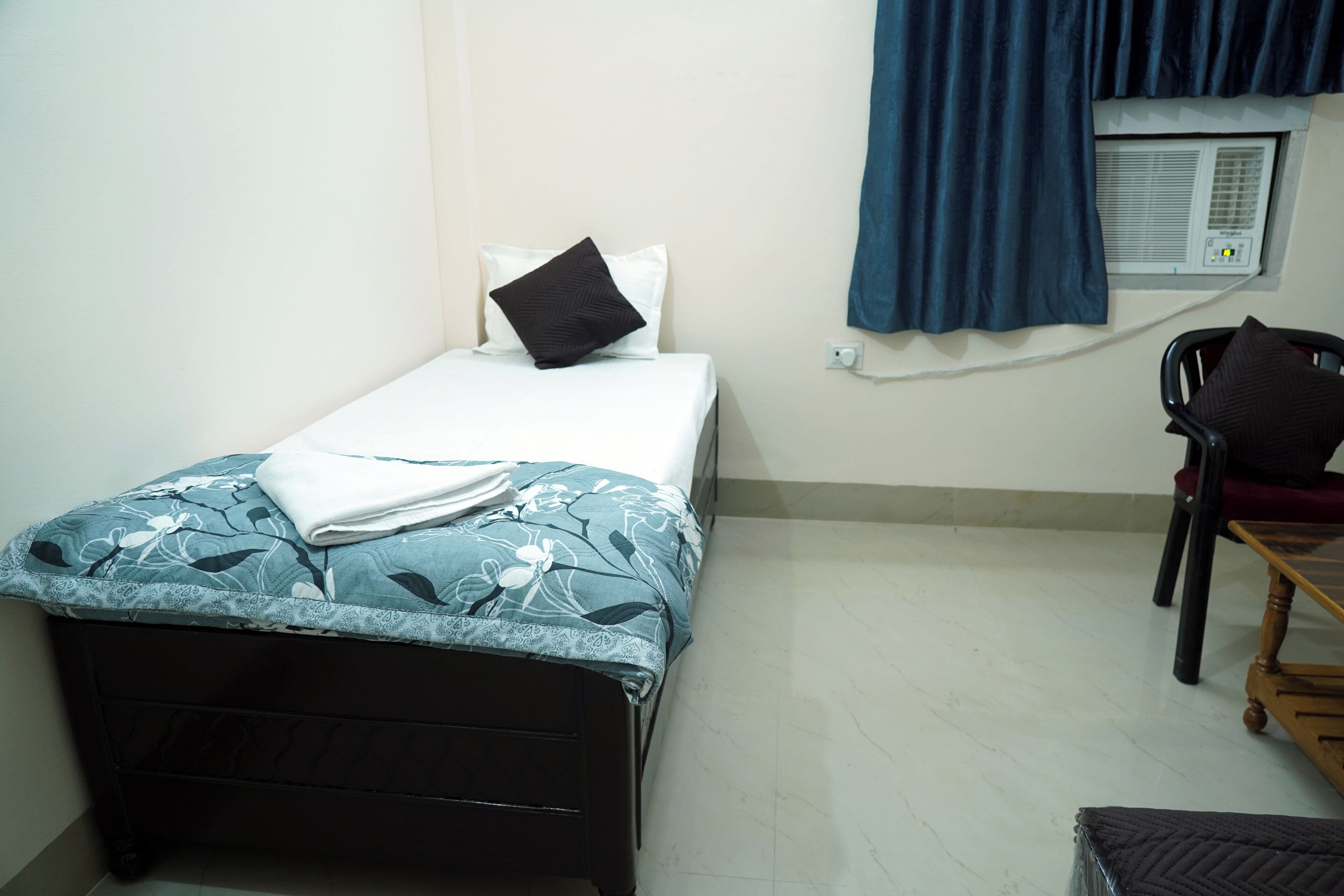 A small, neatly arranged room with a bed, a chair, and a table.