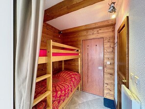 Ein Zimmer mit einem Holzbett mit Etagen und einer Heizungstür.