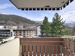 A balcony with a view of a mountain, a building with a sign 'Hotel', and a pine tree. - Studio at the slopes - 4 guests (La Salle-les-Alpes)