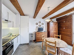Eine Küche mit Herd, Spüle und Schränken, ein Holzessttisch mit Stühlen und eine Holzwand.
