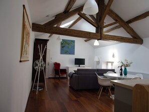 Un salon moderne avec un plafond en bois, un canapé, un téléviseur et un coin repas.