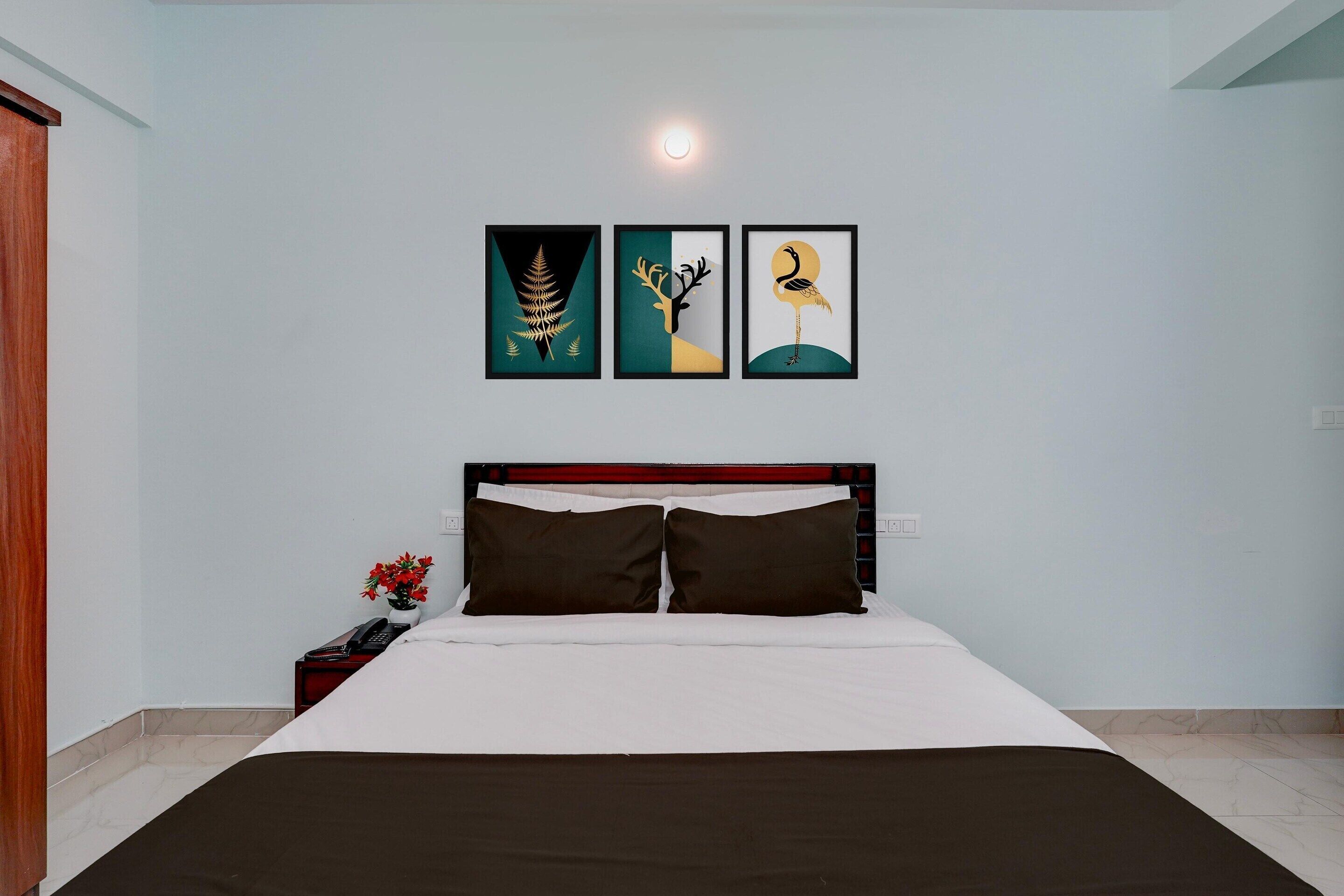 A bedroom with a bed, a nightstand with a phone, and three framed artworks on the wall.
