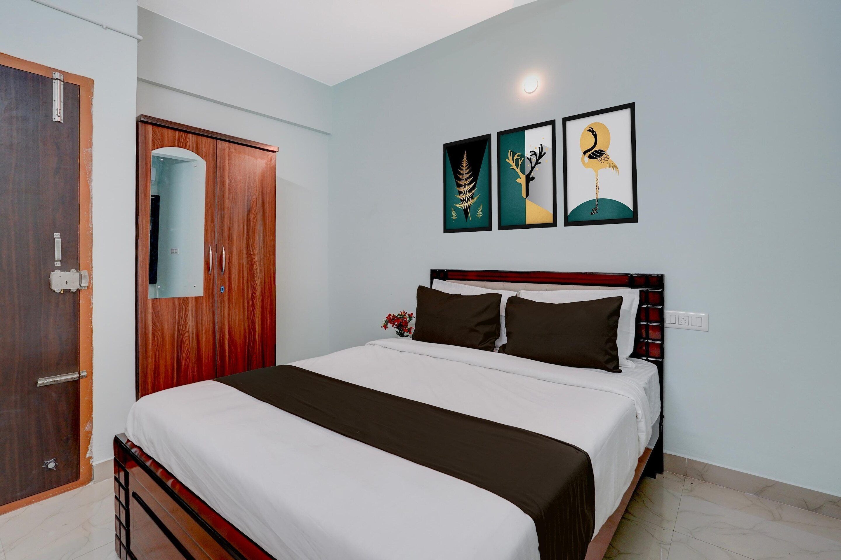 A bedroom with a bed, a wardrobe, and two wall-mounted artworks.