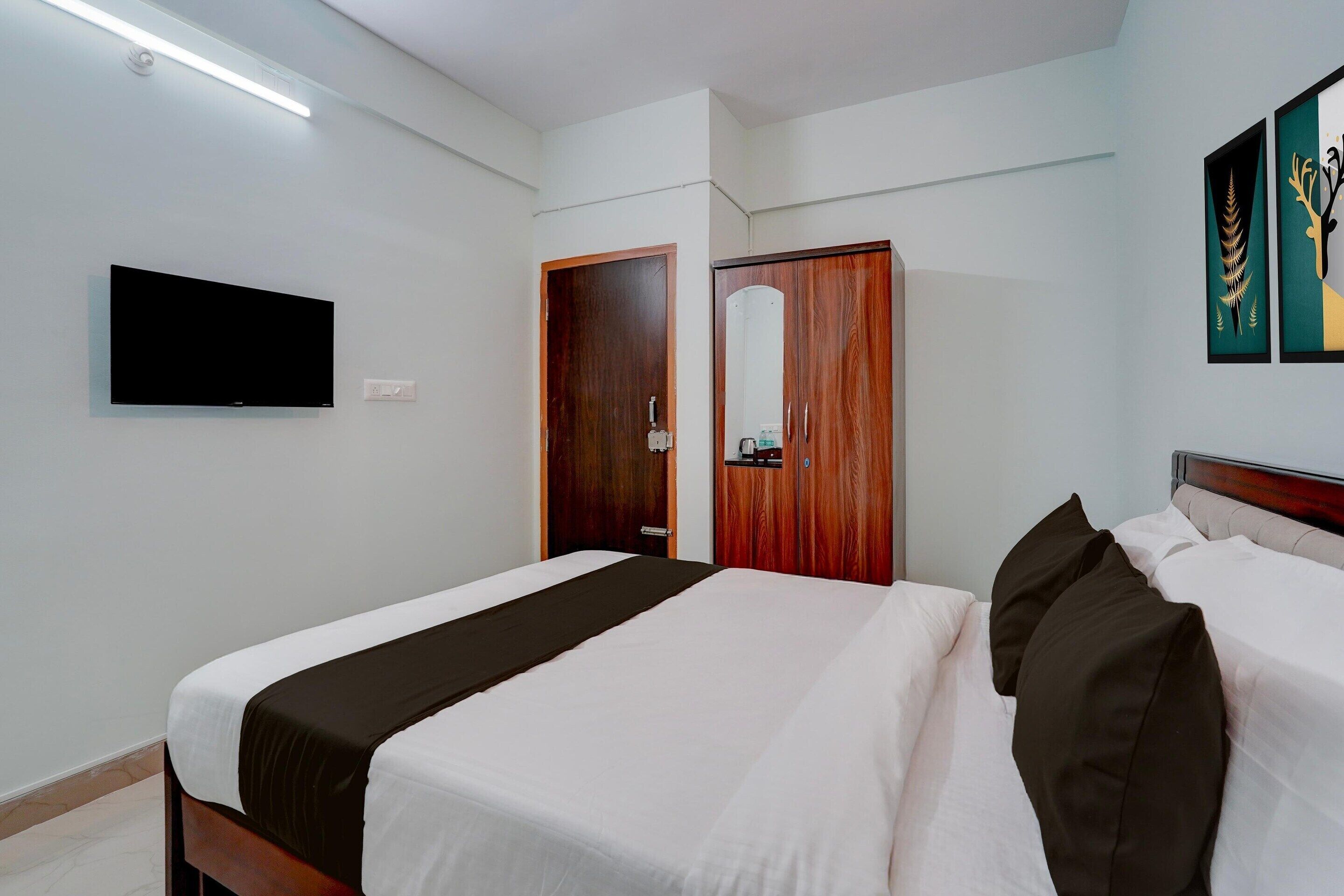 Una camera d'albergo con un letto, un armadio, una televisione e opere d'arte alle pareti.