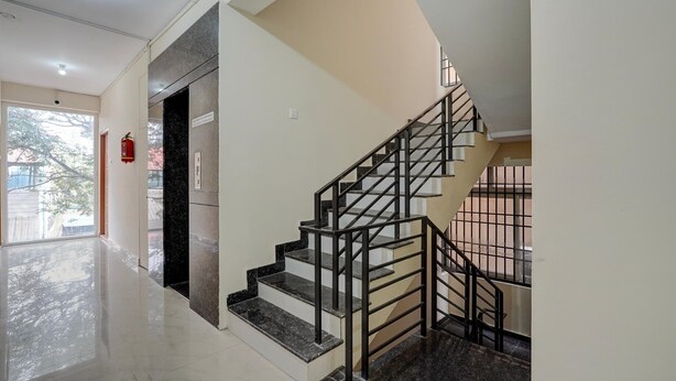 A staircase with a metal railing, a fire extinguisher on the wall, and a door leading to another room. - Deluxe Venkat Inn (Bengaluru)