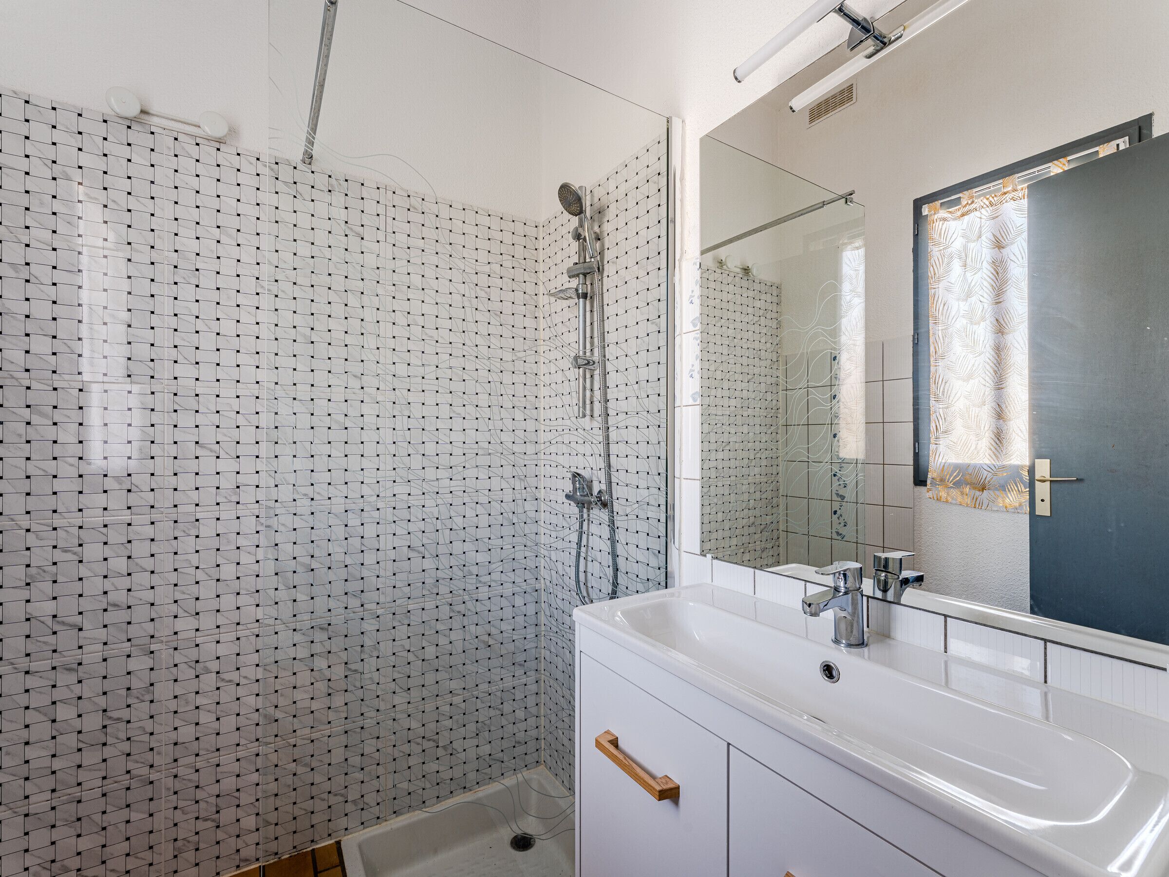 A modern bathroom with a shower, a sink, and a mirror.