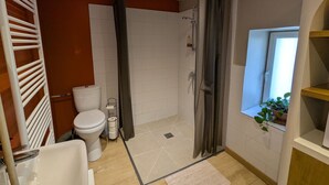 Een badkamer met douche, toilet en wastafel.