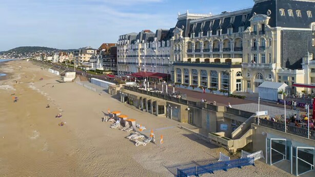 Ett hotell vid kusten med utsikt över stranden, flera våningar och en framträdande entré.