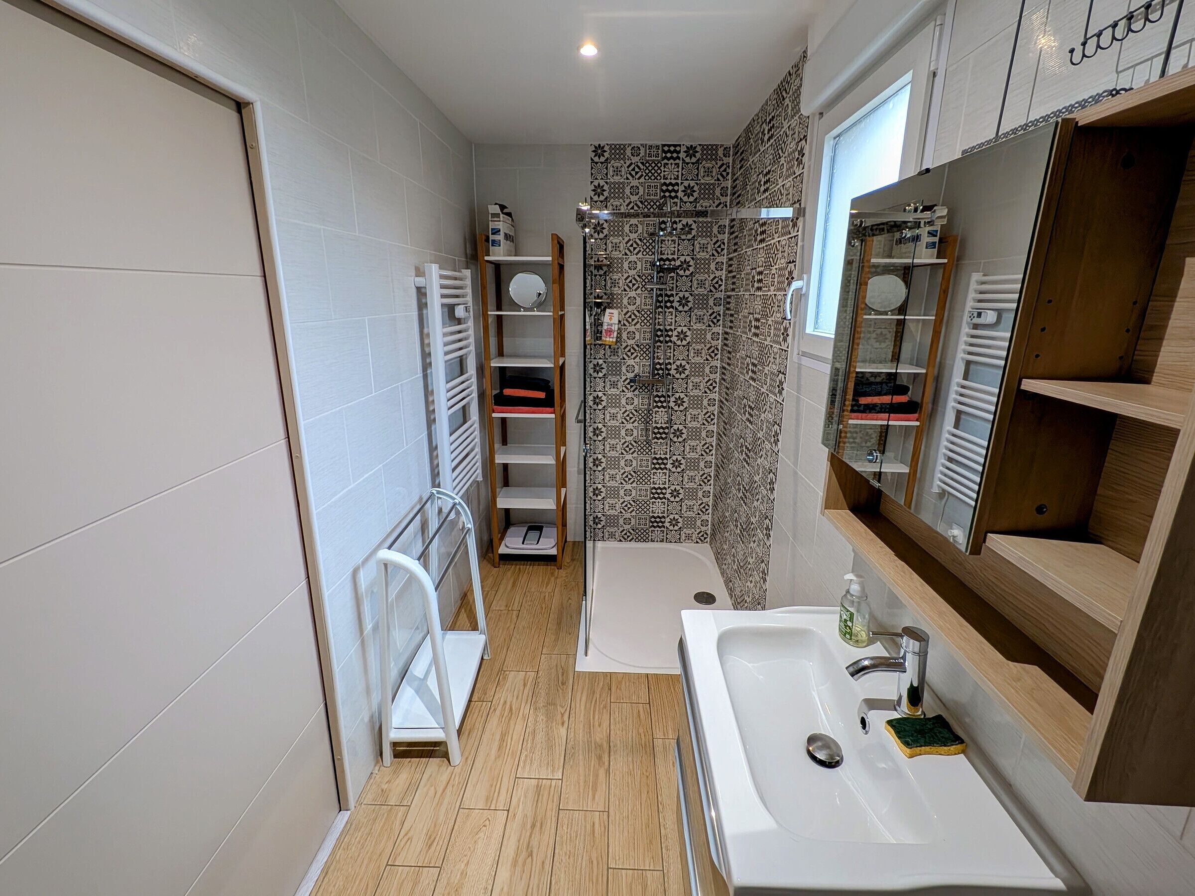 A modern bathroom with a large sink, a shower, and a mirror.