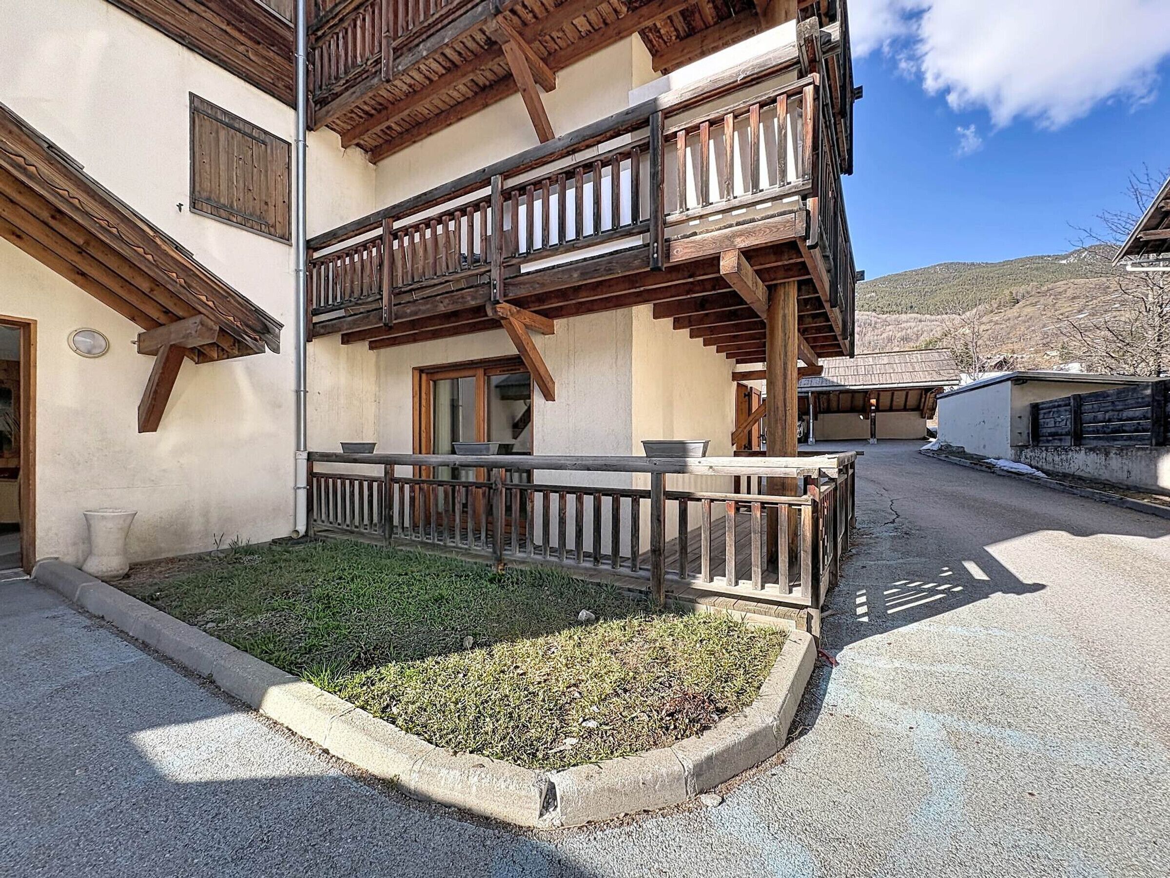 A traditional chalet with wooden balconies, a small garden area, and a clear view of the surrounding landscape.