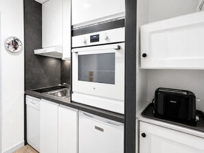 Eine moderne Küche mit weißen Schränken, einem Einbauofen, einem Geschirrspüler und einem schwarzen Toaster.