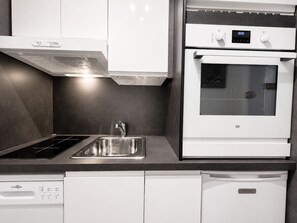 A modern kitchen with a built-in oven, a dishwasher, and a stainless steel sink. - Studio 2 pers - Ski-in at La Croisette (Les Menuires)