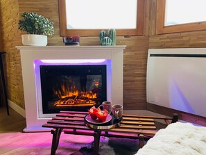 Ein gemütliches Zimmer mit Kamin, einer Tafel mit Snacks und einer Bank.